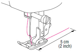 Faites passer l’extrémité du fil dans le pied-de-biche, puis tirez environ 5 cm (2 po)